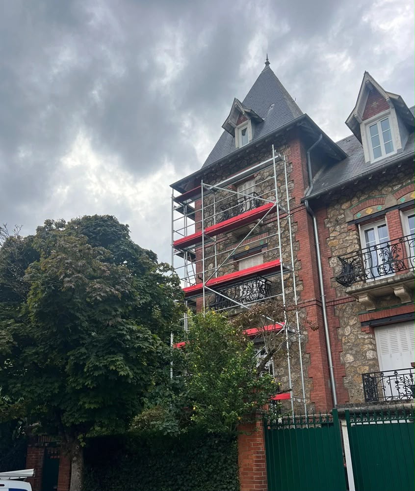 Échafaudage monté le long d'une façade en meulière avant travaux de couverture